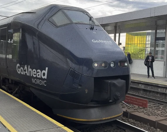 A passenger train approaches a station from the left.